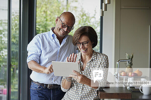 Happy woman with man talking on video call through tablet PC