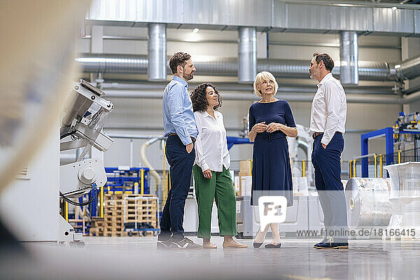 Senior businesswoman talking with colleagues in factory