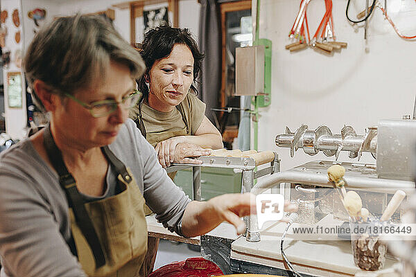 Reifer Töpfer mit Kollegen  der in der Keramikwerkstatt arbeitet