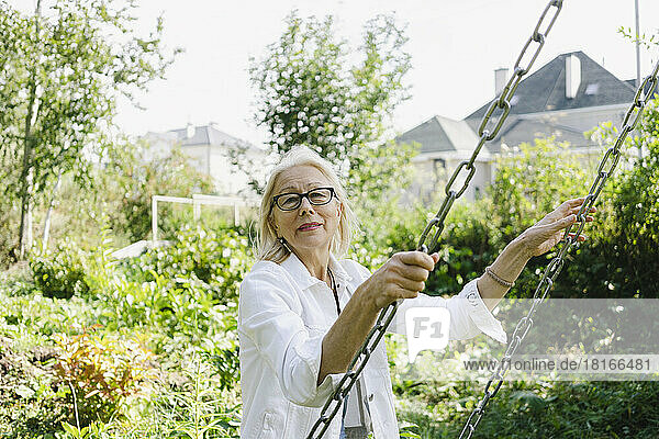 Ältere Frau hält Schaukelkette im Garten