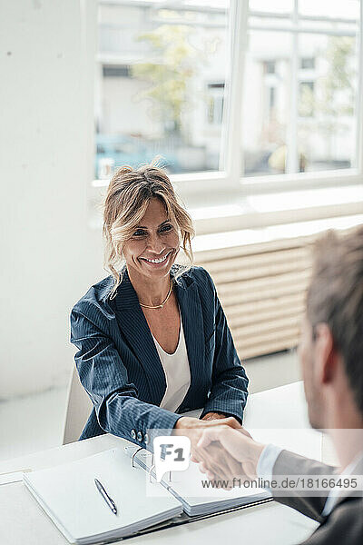 Smiling businesswoman shaking hands with man at office