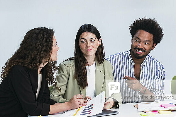 Businessman and two businesswomen discussing document in office