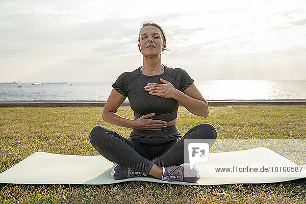 Mature woman doing breathing exercise on grass