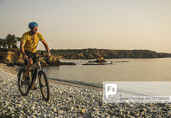 Glücklicher Mann  der am Strand Fahrrad fährt
