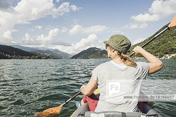 Mature woman kayaking at lake on sunny day