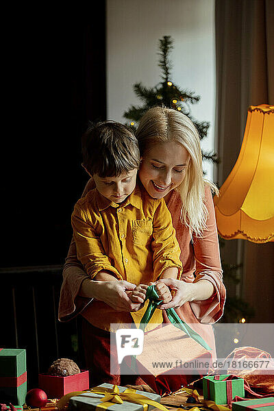 Mother teaching son to wrap gifts at home