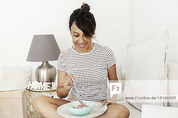Smiling woman having breakfast in living room at home