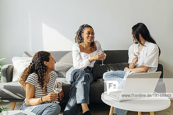 Smiling roommates with wine talking in living room