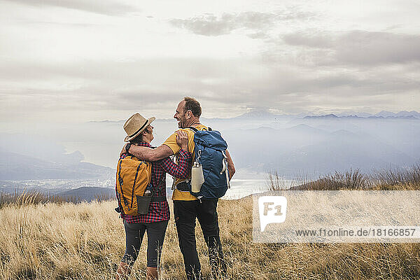 Happy mature couple with backpack standing on grass