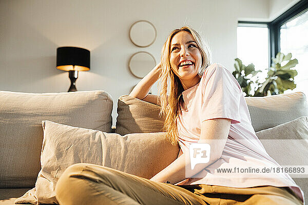 Happy woman sitting on sofa at home