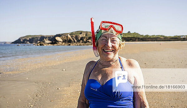 Cheerful woman wearing diving goggles and snorkel mask at beach