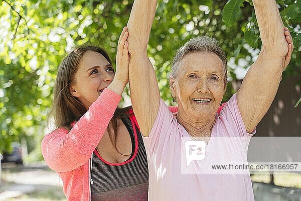 Active senior woman with fitness instructor exercising in park
