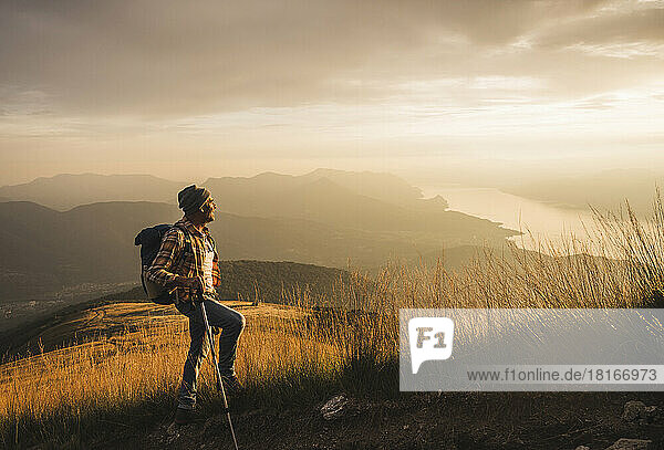 Mature man holding hiking pole looking at sunrise