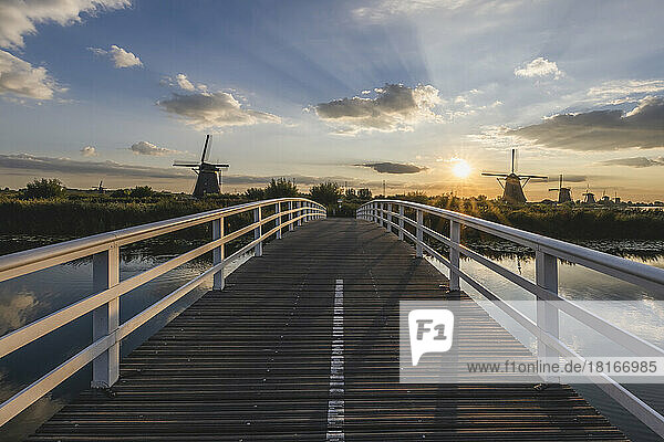 Netherlands  South Holland  Kinderdijk  Countryside bridge at sunset with historic windmills in background