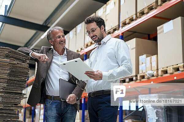 Happy senior businessman with colleague discussing over document at warehouse