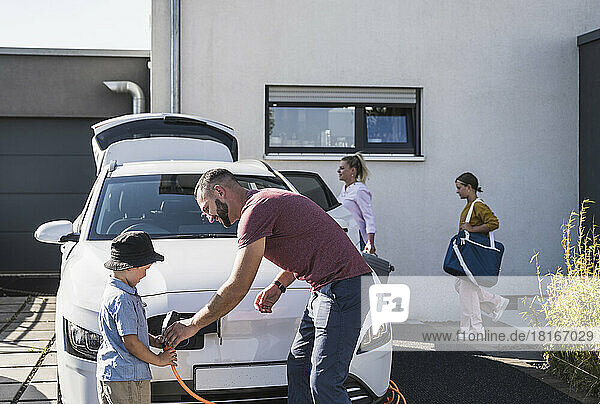 Vater und Sohn laden Elektroauto für den Familienurlaub auf