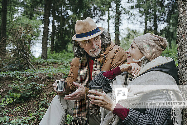 Woman with senior man having tea sitting in forest