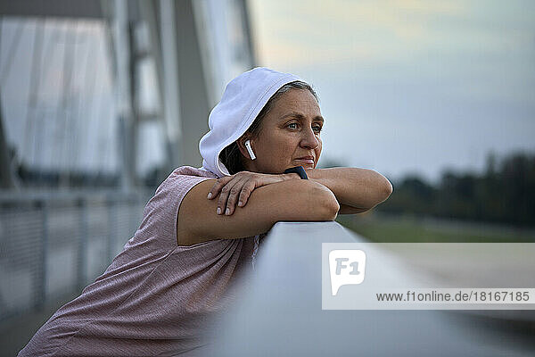 Thoughtful woman day dreaming leaning on railing