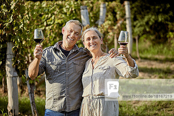 Happy mature couple holding wineglasses on sunny day