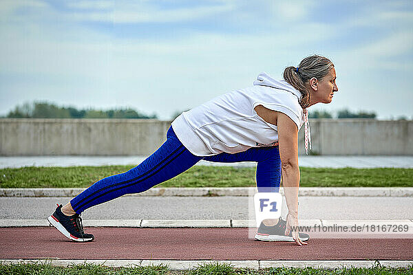 Mature woman preparing for run at sports track