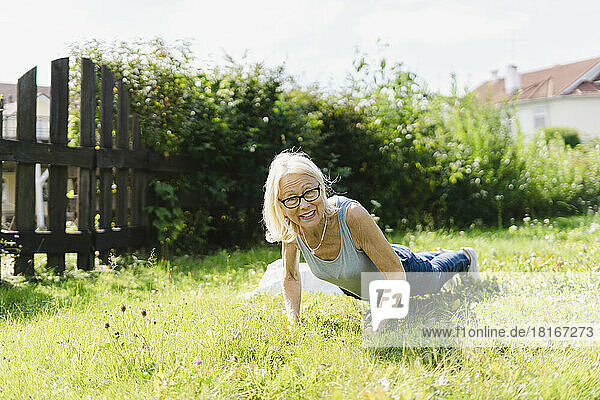 Ältere Frau übt Liegestütze auf Gras im Garten