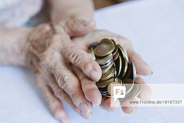 Wrinkled hands of senior woman holding coins