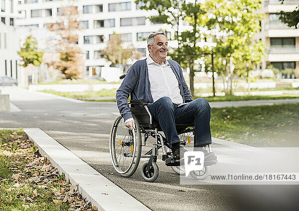 Smiling senior man in sweater sitting on wheelchair