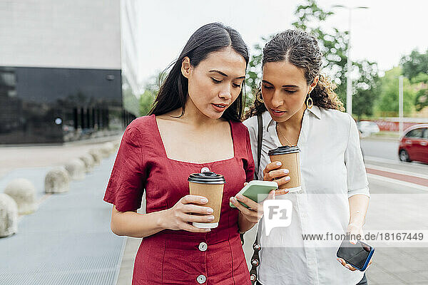 Woman sharing smart phone with friend