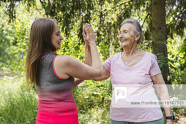 Smiling fitness instructor touching hand of senior woman exercising at park