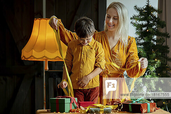 Glückliche Mutter mit Sohn  die zu Hause Geschenke mit Schleife verpackt