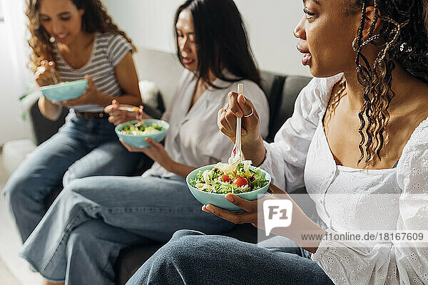 Woman eating salad with friends at home