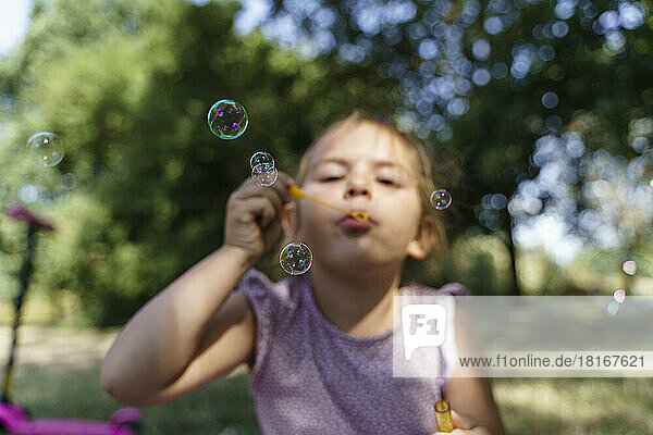 Girl blowing soap bubbles in park