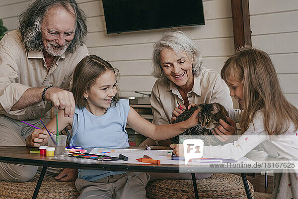 Großeltern und Enkelkinder spielen zu Hause mit der Katze