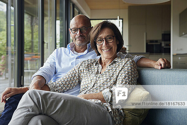 Fröhliche ältere Frau mit Mann sitzt zu Hause auf dem Sofa