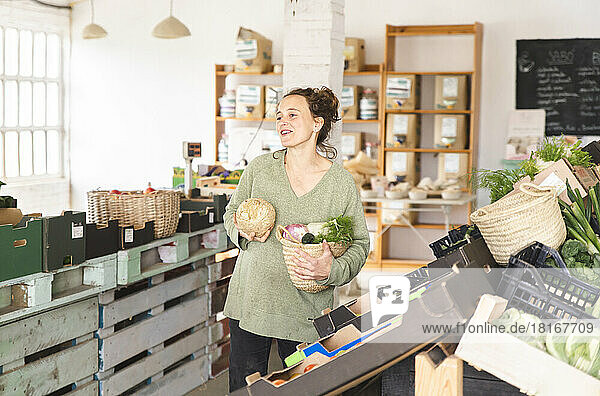 Smiling customer holding vegetables in greengrocer shop