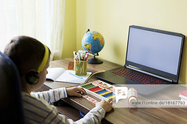 Boy sitting with block of number doing online schooling at home