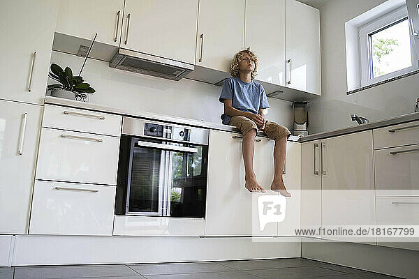 Boy sitting on kitchen counter at home