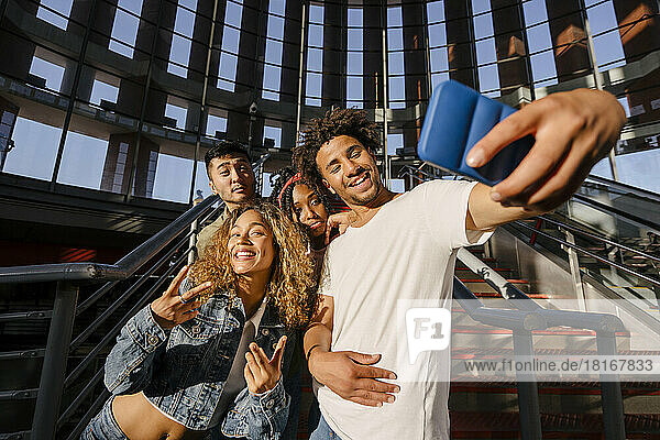 Lächelnde  gemischtrassige Freunde  die am Bahnhof ein Selfie mit dem Handy machen