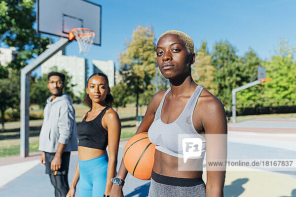 Selbstbewusste Sportlerin mit Basketball von Freunden vor Gericht