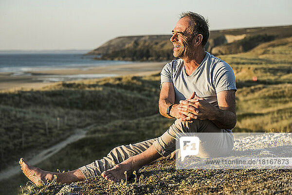 Happy mature man enjoying on hill at sunset