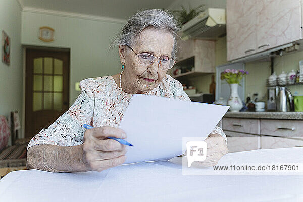 Senior woman reading contract papers at home