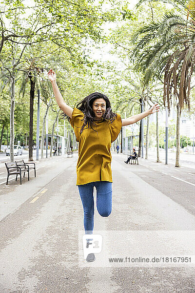 Happy woman jumping on footpath in the city