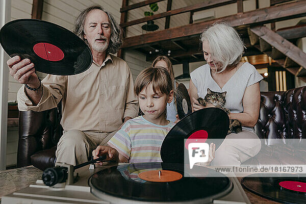 Granddaughter changing record on turntable with grandparents at home