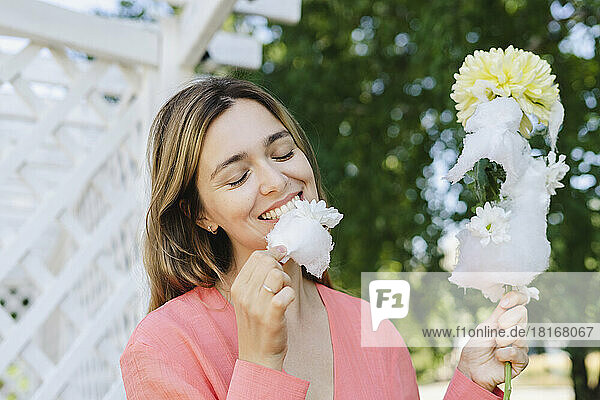 Glückliche Frau  die Zuckerwatte mit Blume isst