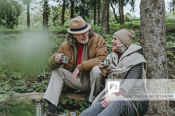 Happy couple enjoying hot tea in forest