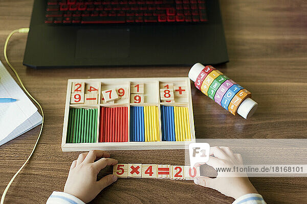 Hand's of boy arranging number blocks at home