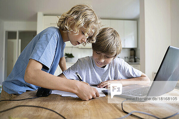 Boy assisting brother doing homework at home