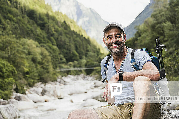 Happy mature man sitting in front of mountains