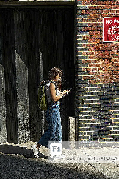 Frau benutzt Smartphone und geht auf Fußweg