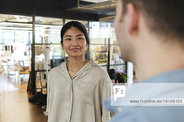 Young woman talking to colleague in modern coworking space